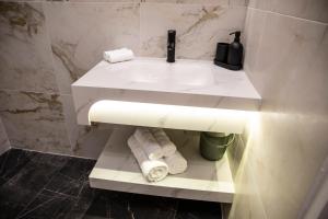 a bathroom with a sink and towels on a shelf at Maison Caliya in Saint-Didier-en-Velay