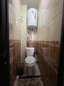 a small bathroom with a toilet and a light at Guest House URUYAT in Naryn