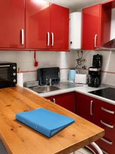 a kitchen with red cabinets and a blue laptop on a wooden table at ESTUDIO Torrevieja P & A - Piscina y Playa La Mata 3 min in La Mata