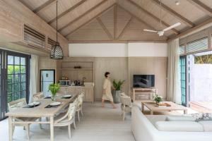 a woman walking through a living room with a table and chairs at Flora Creek Chiang Mai in Hang Dong