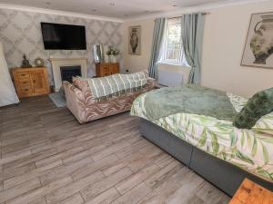 a bedroom with a bed and a couch and a tv at Annexe Meadows Farm in Swansea