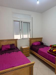 two beds in a room with purple sheets at RiF Services in Al Hoceïma