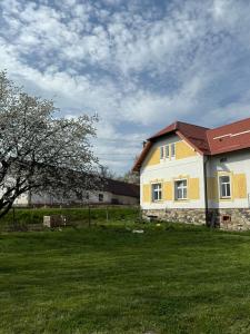 a yellow and white house in a grass field at Statek Osmička in Dolní Hořice