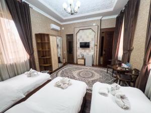 a hotel room with two beds and a table at Hotel Gold Begim in Fergana