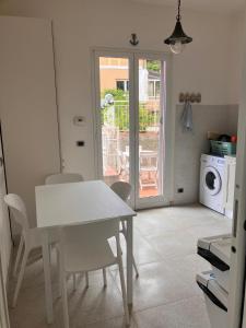 a white table and chairs in a kitchen with a door at Verdazzurra in Bergeggi +24 photos