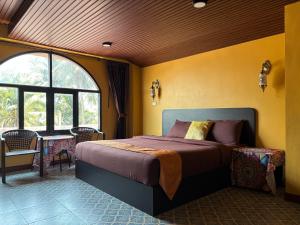 a bedroom with a bed in a room with a window at Phoenix Room in Ban Tha Samet (1)