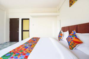 a bedroom with a white bed with a colorful blanket at FabHotel Infinity Residency in Pune