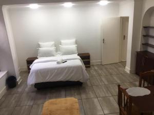 a bedroom with a bed with white sheets and pillows at Zanem Guest House in Potchefstroom