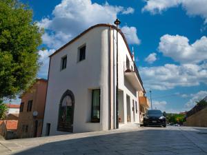 a white building with a car parked on a street at ANTICHE TERRE Di GALLURA in Monti