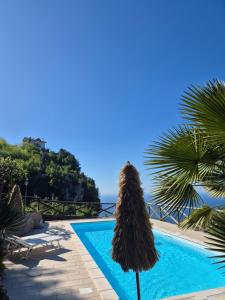 an umbrella next to a swimming pool with the ocean at La Cicogna in Agerola