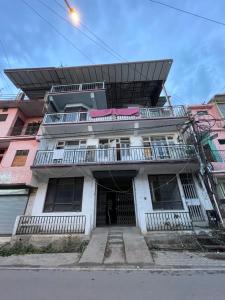 a white building with a balcony on top of it at Tatva stays in Dharmsāla