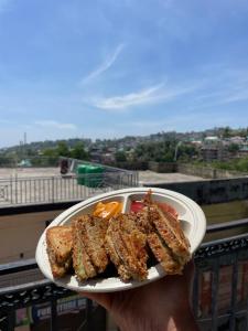 a person holding a plate of food in their hand at Tatva stays in Dharmsāla