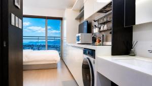 a kitchen with a sink and a washing machine in a room at Shine Hotel Incheon Airport in Incheon