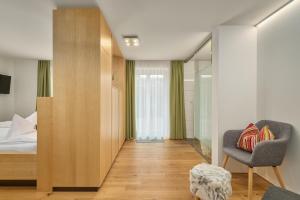 a bedroom with a bed and a chair and a window at OXA - Easy Escape - Bed & Breakfast in Hittisau