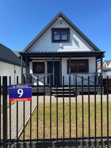 a house with a sign in front of a fence at Domki Prima Baltic in Sarbinowo