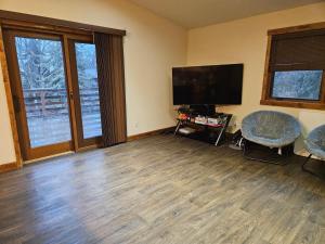 an empty living room with a flat screen tv and a table and chairs at River View Upstairs Apartment in Kenai