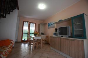 a living room with a television and a table with chairs at Villetta a schiera Salina con giardino privato e portico in Rosolina Mare +37 photos