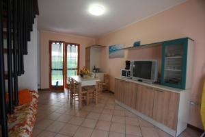 a living room with a kitchen with a table and a tv at Villetta a schiera Salina con giardino privato e portico in Rosolina Mare