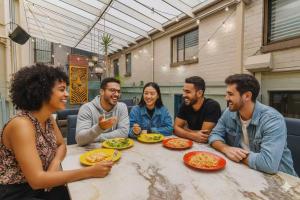 a group of people sitting at a table with plates of food at London Gate Backpackers Hostel in Sydney