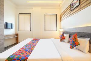 a bedroom with a large white bed with colorful pillows at FabHotel Kalptaru in Pune