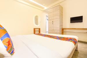 a white bedroom with a bed and a tv at FabHotel Kalptaru in Pune
