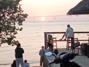 a group of people standing on the beach at sunset at Ladybugs hostel sunset in Taling Ngam Beach