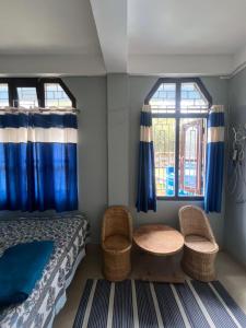 a bedroom with a bed and a table and two windows at Tani Adventure in Ziro