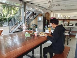 a man sitting at a table with a plate of food at Ladybugs hostel sunset in Taling Ngam Beach