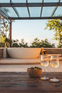 two glasses of wine sitting on a wooden table with a bowl of food at Salty Lotus in Uluwatu