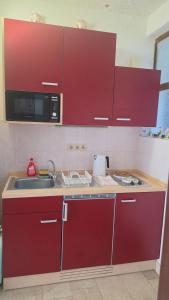 a kitchen with red cabinets and a sink and a microwave at Apartment Antonia in Selce