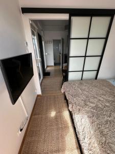 a bedroom with a bed and a flat screen tv at Baltic Lark Gąski domek 30m2, taras zadaszony 27m2 ogródek klimatyzacja in Gąski