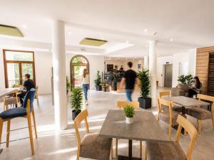 a restaurant with tables and chairs and people walking around at Hotel Vela in Nago-Torbole