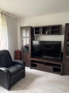 a living room with a black leather chair and a large television at Wohlfühlen bei Tobi in Gelsenkirchen