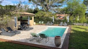 a swimming pool with chairs and a table at Les maisons de loup a loup in Cotignac