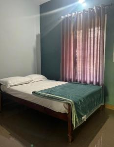 a bed in a room with a window with a curtain at Grass root by shelters in Vayittiri