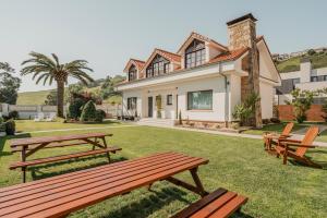 a house with picnic tables in the yard at Villas de La Ribera in Suances