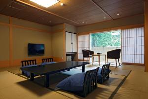 a dining room with a table and chairs and a tv at Notoya in Komatsu