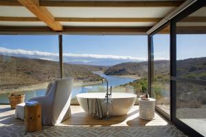 a bathroom with a tub and a view of a river at Aardvark Bioreserve in Ladismith +23 photos