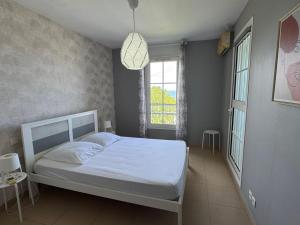 a bedroom with a white bed and a window at Rayon de vacances T3 spacieux et bien équipé in La Possession