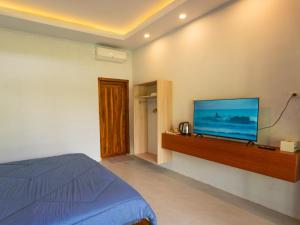 a bedroom with a bed and a flat screen tv at Heyho Bungalow in Maluk