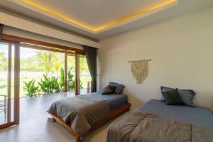 a bedroom with two beds and a large window at Heyho Bungalow in Maluk