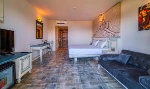 a room with a bed and a couch and a television at Assos Dionysos Special Class Hotel Adults Only 12 years in Behramkale