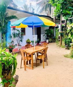 a wooden table with chairs and an umbrella at Green House Holiday Villa in Trincomalee