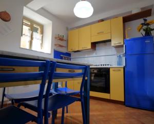 a kitchen with yellow and blue cabinets and a table and chairs at Casa Paola 5 Terre in Biassa
