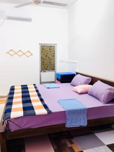 a large bed with purple sheets and pillows on it at Green House Holiday Villa in Trincomalee