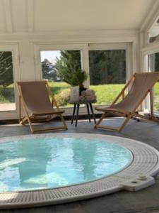 a large swimming pool with two chairs and a table at Yourte chaleureuse in Bois-le-Roi
