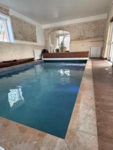 a large swimming pool with blue water in a room at Yourte chaleureuse in Bois-le-Roi