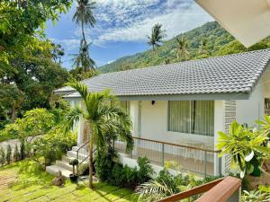 a white house with trees and mountains in the background at Baan Suan Poolsap - Haad Rin Beach in Haad Rin