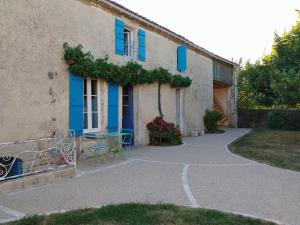 a building with blue shutters and a table in front of it at Le Logis de bouillé in Bouillé-Courdault