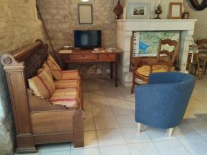 a living room with a couch and a desk and a television at Le Logis de bouillé in Bouillé-Courdault